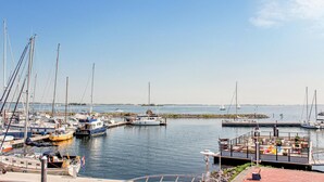 A marina with various boats docked, a small dock with seating, and a clear view of the water and distant land. - Stunning apartment in Bruinisse (Bruinisse)