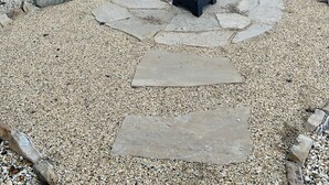 Uma área de pátio com uma lareira de pedra rodeada por pedras e pedregulhos.