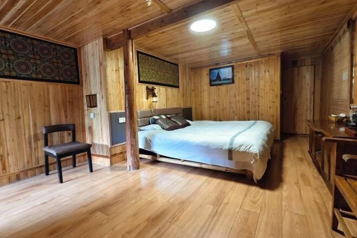 A wooden-paneled room with a bed, a chair, and a desk.