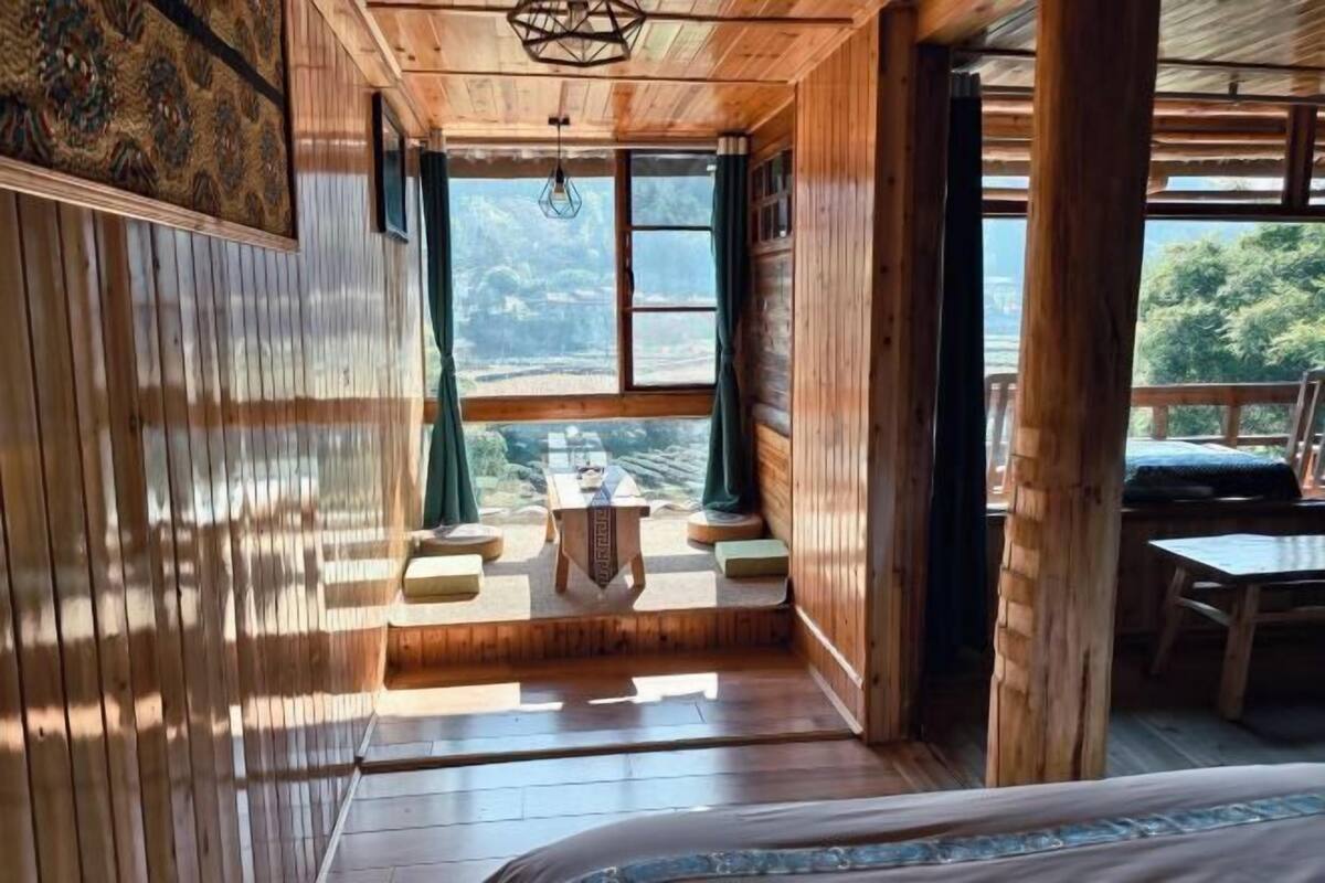 A wooden cabin with a bed, a table, and a view of the outdoors.