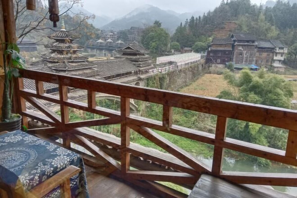 Ein traditioneller Holzbalkon mit Blick auf ein Dorf und Berge.