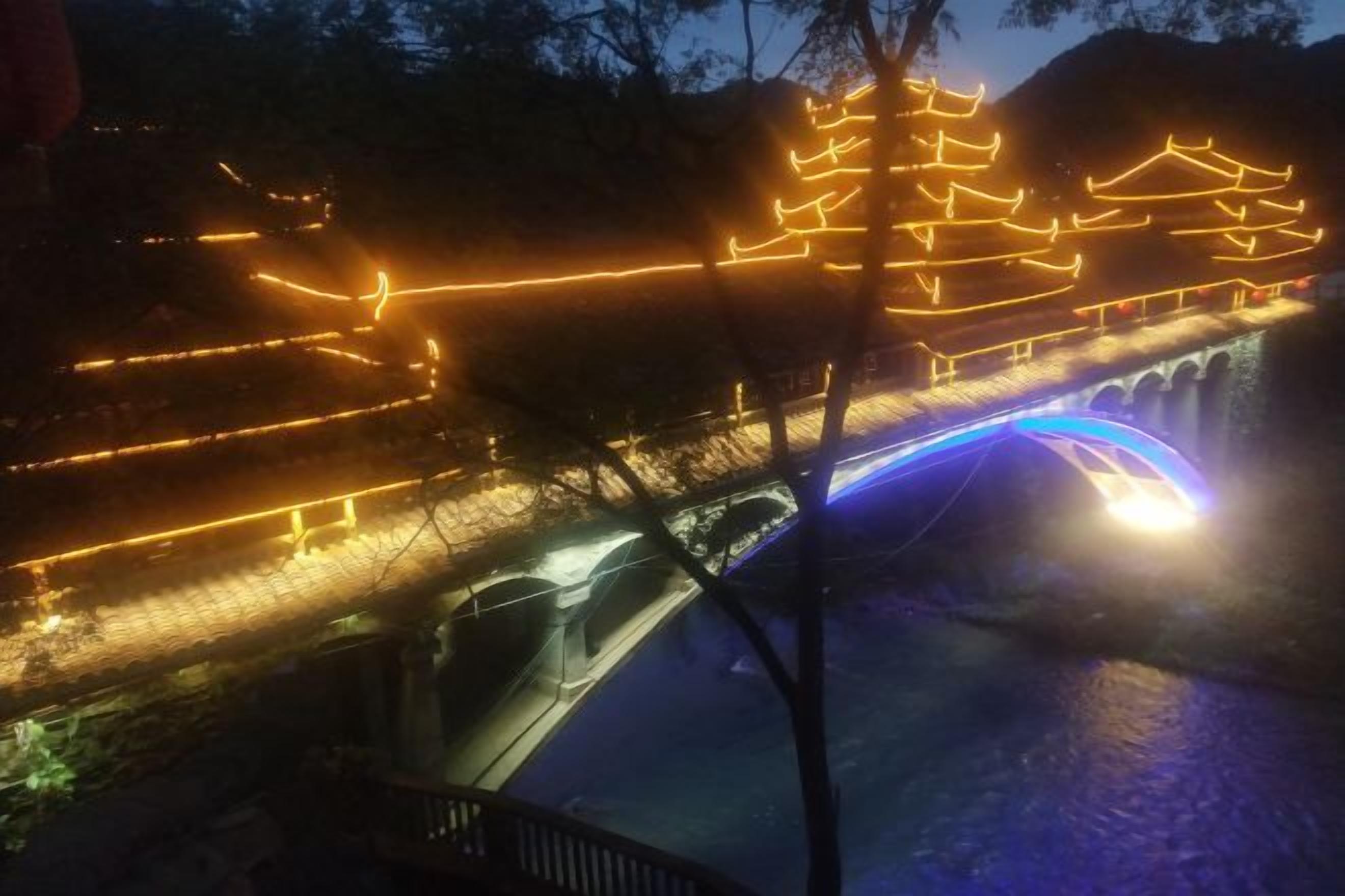 Een brug met verlichte constructies en een rivier.