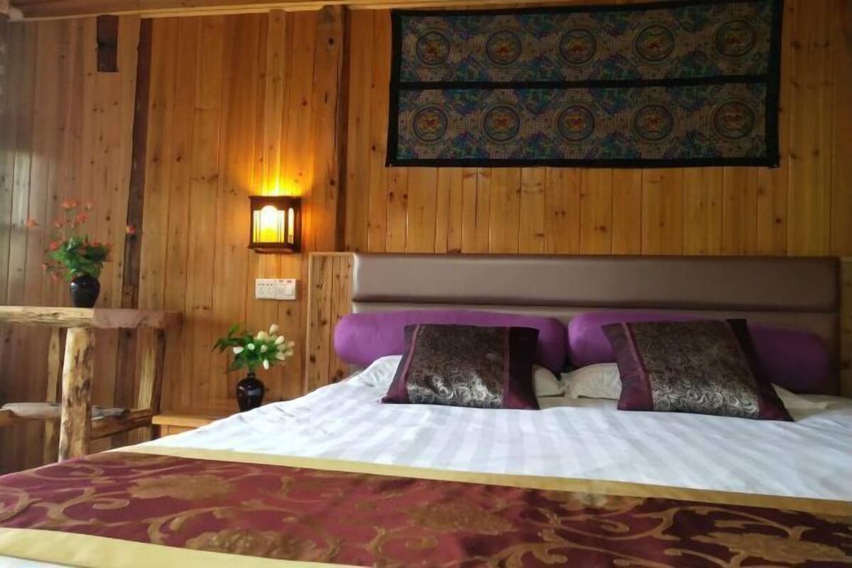 A wooden-paneled room with a bed, a wall-mounted light, and a tapestry.