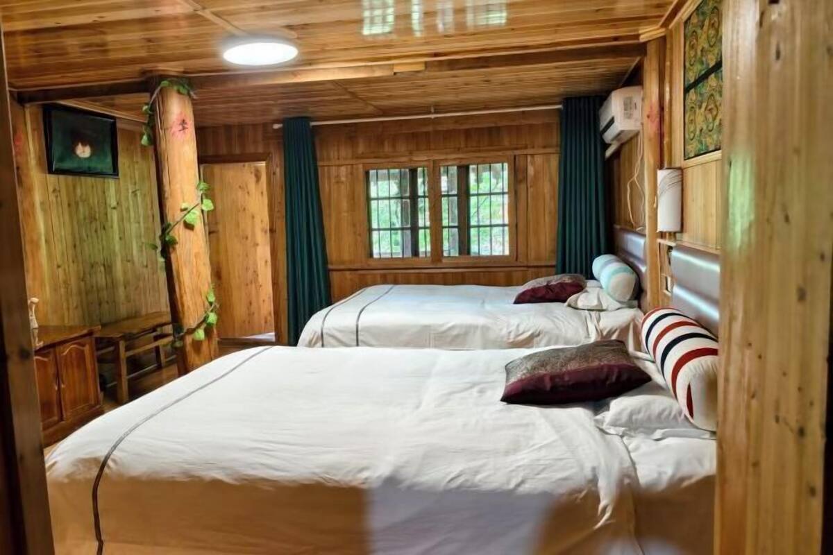 A wooden cabin-style room with two beds, a window, and a wooden cabinet.