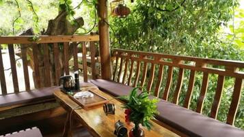A wooden deck with a bench, a table with a plant, and a hanging lantern.