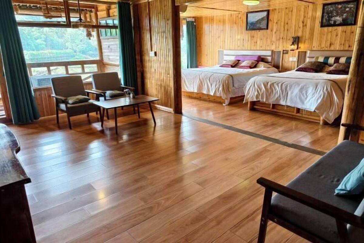 A wooden cabin with two beds, a dining area, and a view of the outdoors.