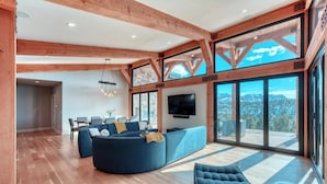 A spacious living area with a large sofa, a television, and a dining area with chairs and a table. - Panoramic Views & Hot Tub near Zion/Bryce (Orderville)
