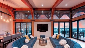 A spacious living area with a large curved sofa set, a flat-screen TV, and a dining table with chairs. - Panoramic Views & Hot Tub near Zion/Bryce (Orderville)