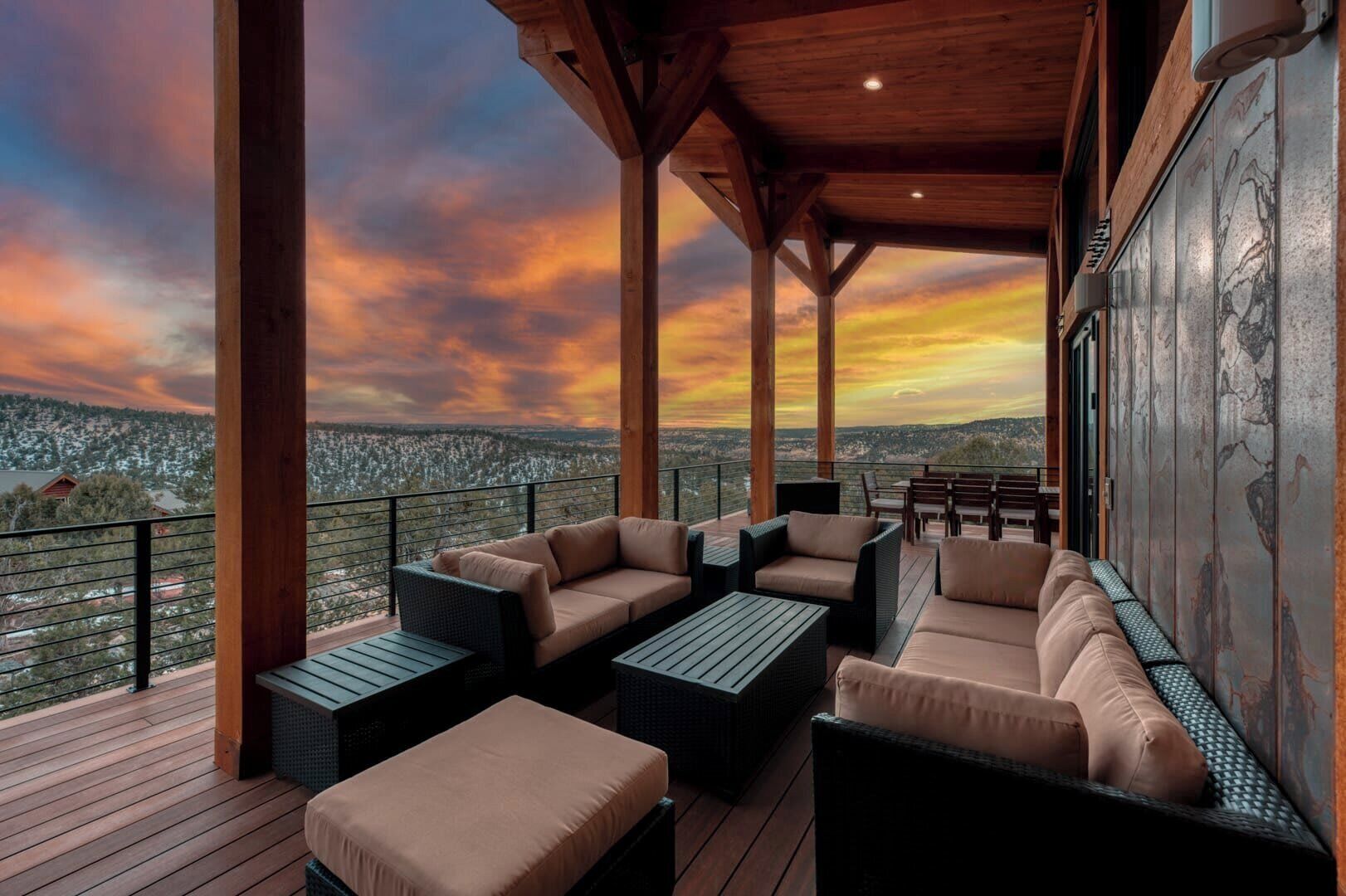 Uma área de estar coberta ao ar livre com vista para um horizonte urbano ao pôr do sol.