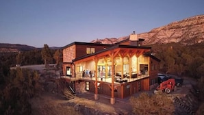A modern two-story building with a balcony, surrounded by a mountainous landscape. - Panoramic Views & Hot Tub near Zion/Bryce (Orderville)