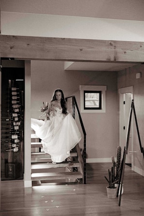 A staircase with a person in a wedding dress, a framed picture on the wall, and a cactus plant.