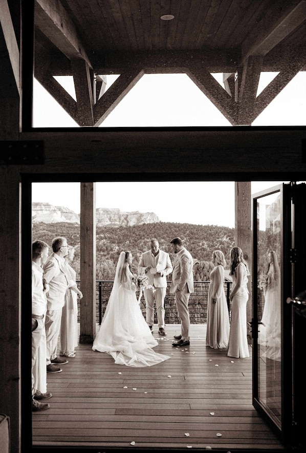 A wedding ceremony on a wooden deck with a mountainous backdrop.