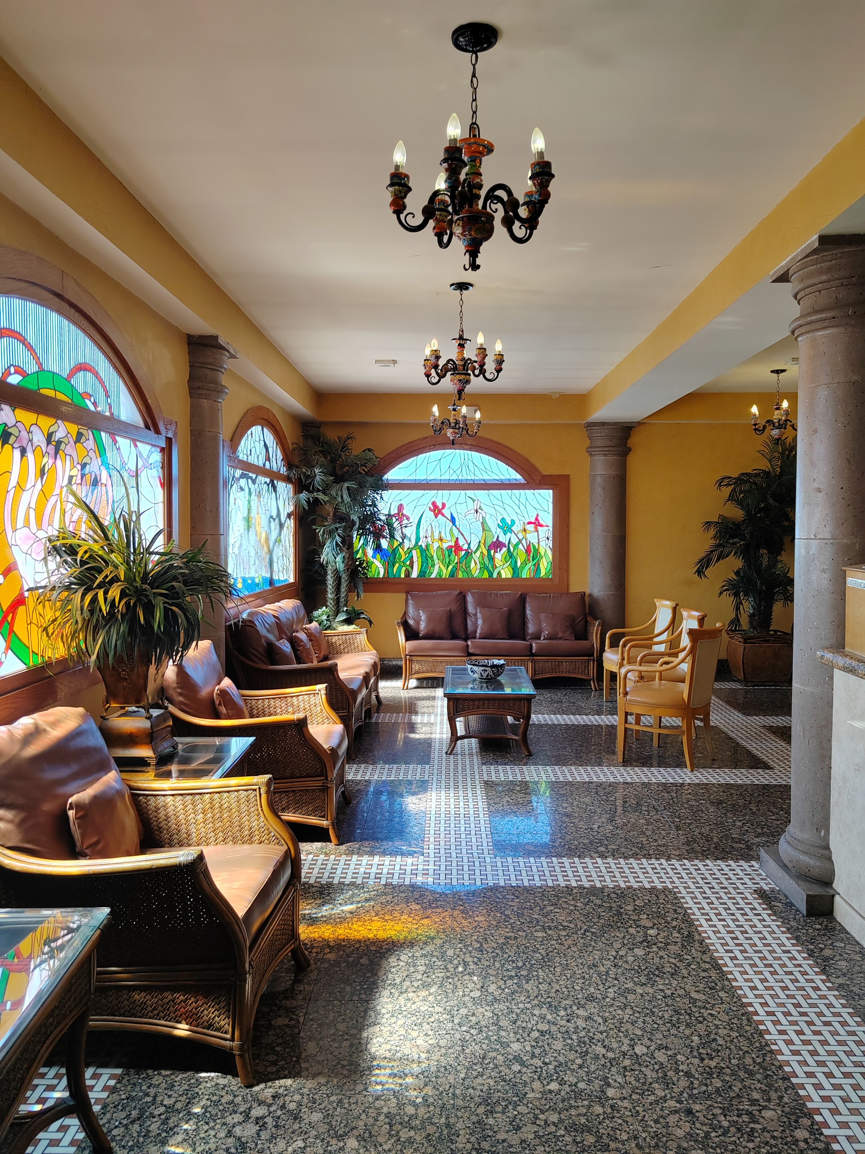 A lobby with a chandelier, sofas, chairs, and a coffee table.