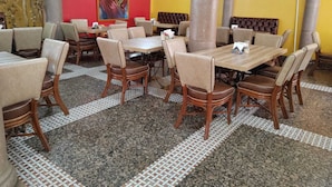 Un restaurant amb diverses taules i cadires, un ventilador de sostre i un quadre gran a la paret.