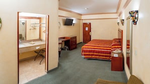 Una habitació d'hotel amb llit, escriptori, cadira, mirall i televisió.