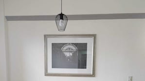 Una habitació amb dos armaris beix, una taula rodona petita, una làmpada de ferro negre i un quadre amb marc a la paret.