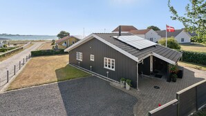 A coastal building with a gravel driveway, a covered porch, and a flag. - Awesome home in Broager (Broager)