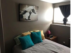 Relax in a serene space with a large bed, a bedside table, and a beautiful painting of a horse.