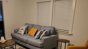 A living room with a gray sofa, yellow armchair, and a patterned rug. - Aunt Mattie's Cottage (Ocean Springs)