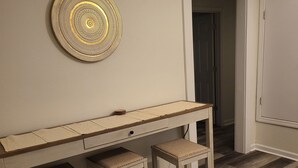 A room with a wooden desk, two matching stools, and a decorative wall piece. - Aunt Mattie's Cottage (Ocean Springs)