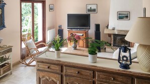 Ein gemütliches Wohnzimmer mit Fernseher, Kamin und bequemen Sitzgelegenheiten.