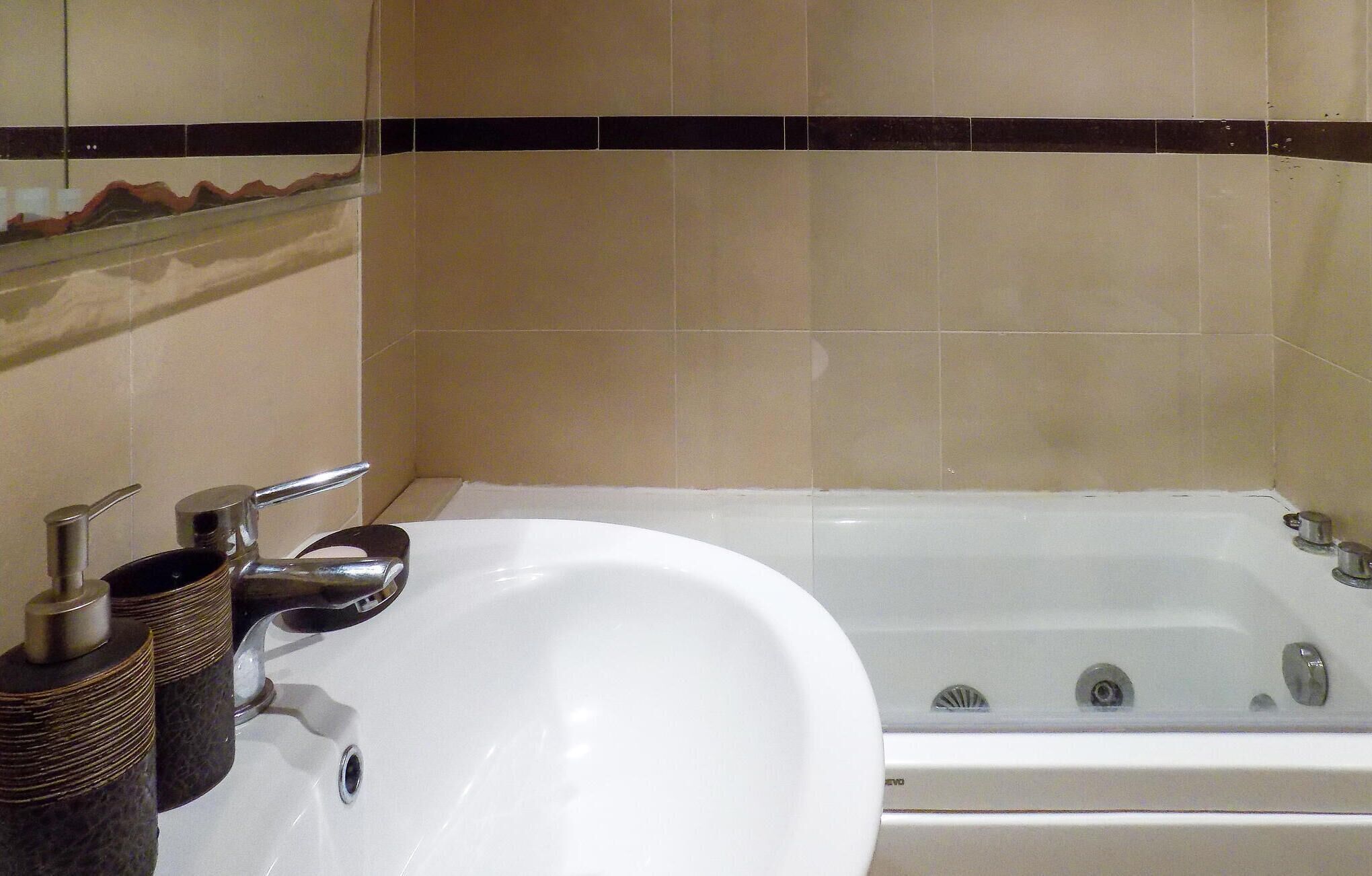 A bathroom with a white sink, a bathtub, and a mirror above the sink.