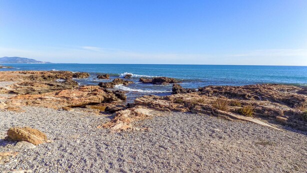 Ein felsiger Strand mit Kieselsteinen und Wellen.