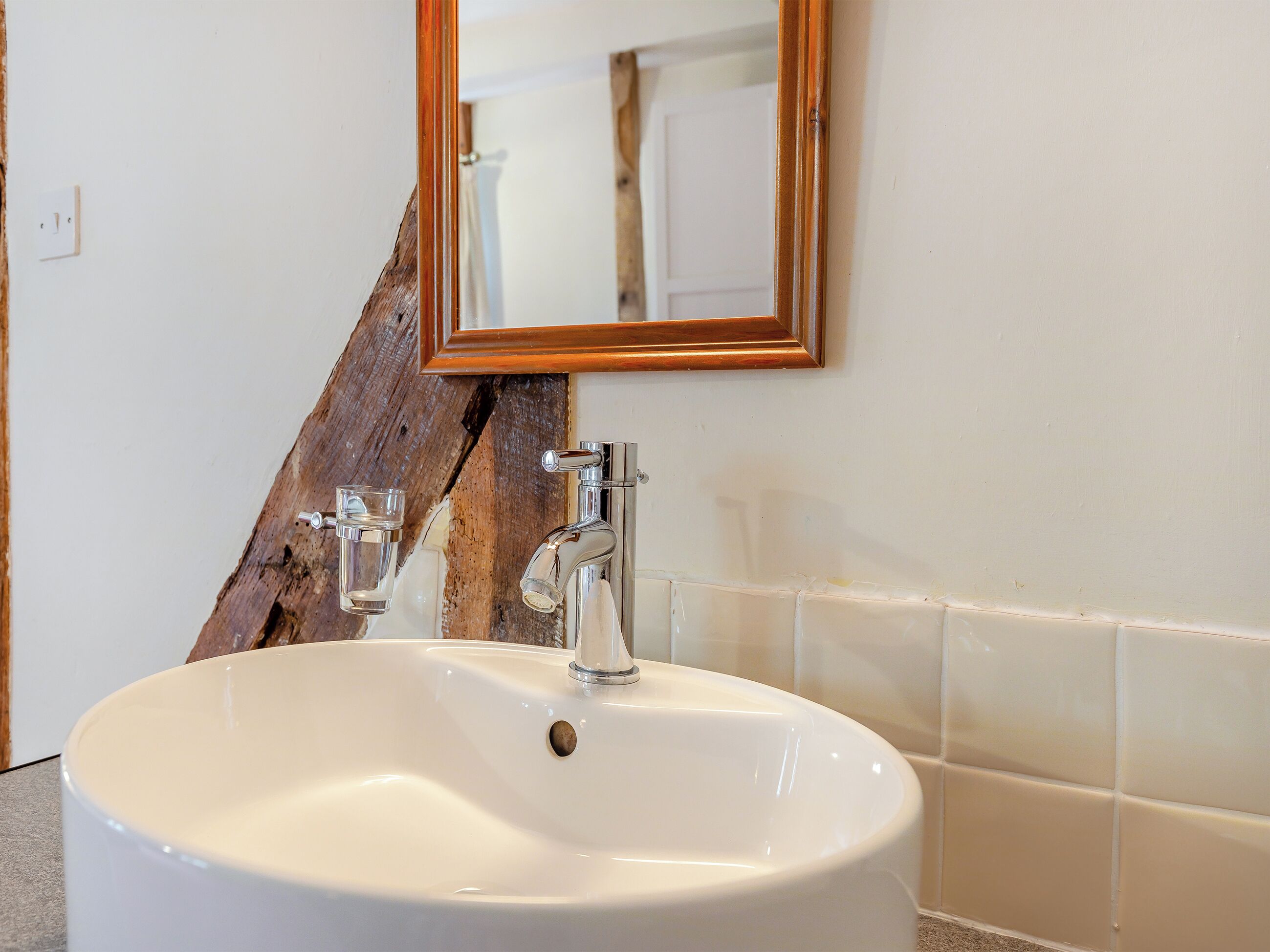 Un bagno con un lavandino bianco, due rubinetti e una parete decorativa in legno.
