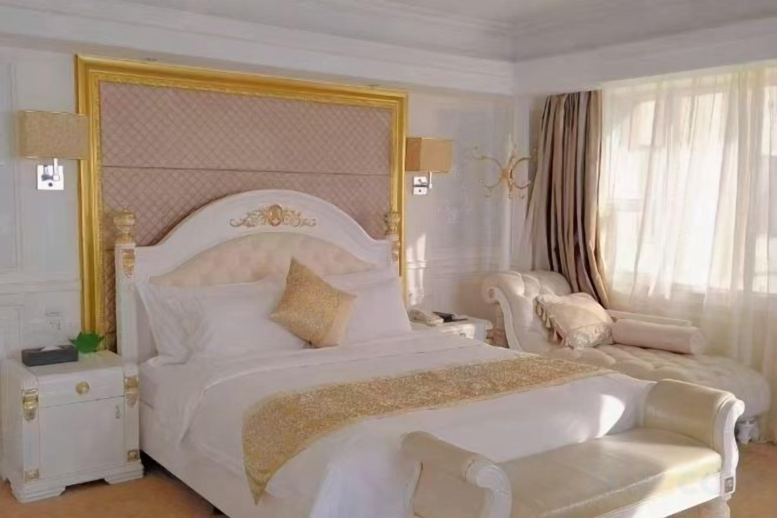 A hotel room with a large bed, a nightstand, a chair, and a window with curtains.