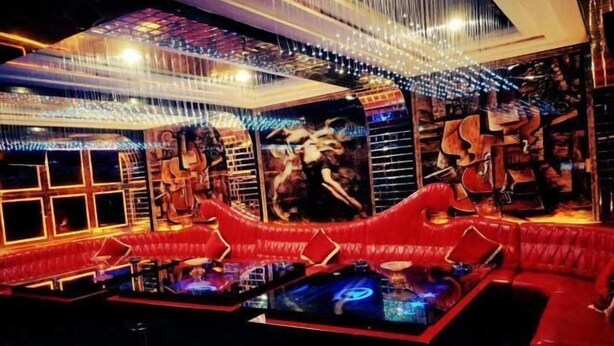 Espaço de bar com assentos vermelhos, mesa de bilhar e um mural de músicos.