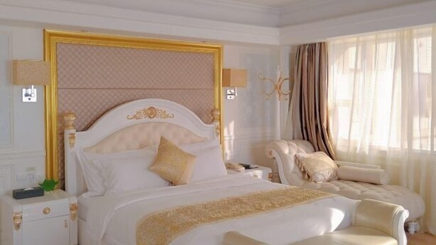 A luxurious bedroom with a large bed, a nightstand, a chair, and a chandelier. - Jinjiacheng Hotel (Shantou)