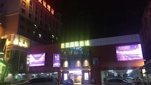 A hotel entrance with illuminated signage and a parking area. - Jinjiacheng Hotel (Shantou)