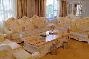 A luxurious living room with ornate sofas, a marble coffee table, and a large window with curtains. - Jinjiacheng Hotel (Shantou)