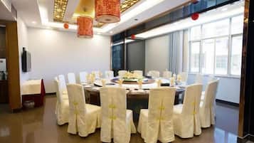 A conference room with a round table, white chairs, and red hanging lamps.