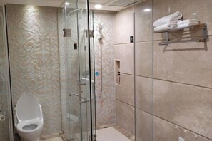 Un bany modern amb dutxa de vidre, vàter i paraigua per a tovalloles.
