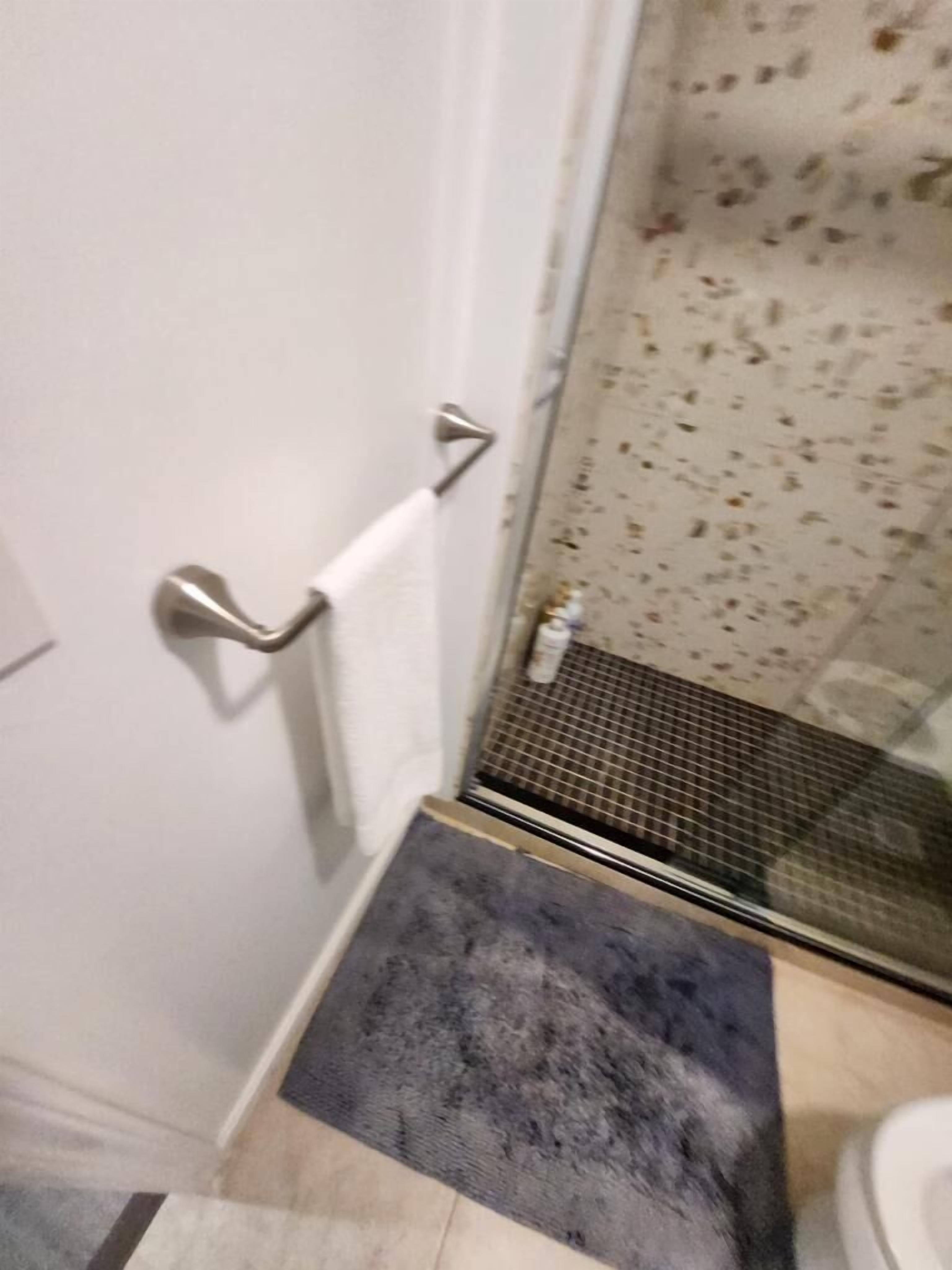 A bathroom with a shower area, a towel rack, and a tiled floor.