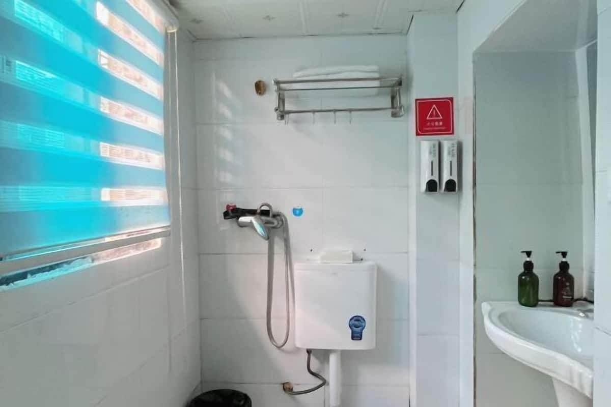 Un baño con ducha, lavabo y toallero.