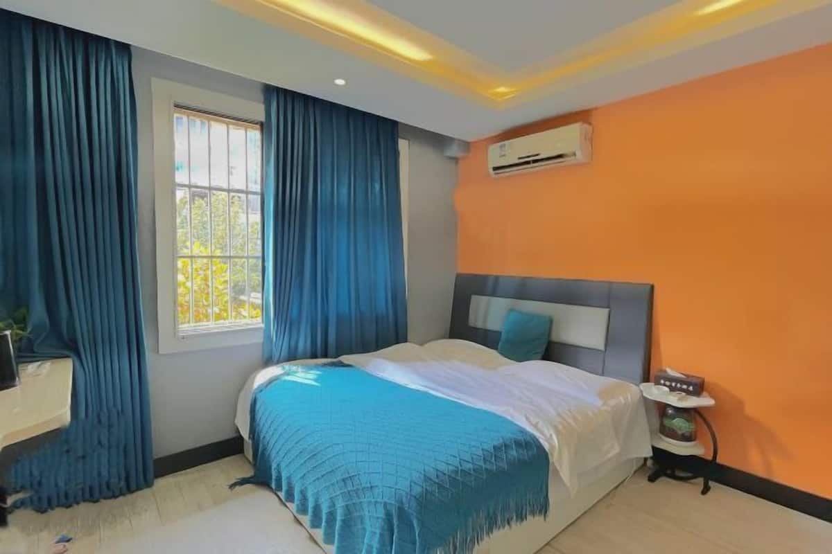 Un dormitorio con cama, ventana con cortinas, aire acondicionado y mesita de noche.