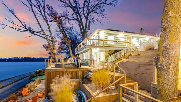 Ein Wohnhaus direkt am Wasser mit einer mehrstufigen Terrasse, Sitzgelegenheiten im Freien und einer Treppe zu den oberen Ebenen.