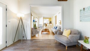 Ein geräumiges Wohnzimmer mit Sofa, Couchtisch und Lampe. Im Hintergrund ist eine Küche zu sehen.