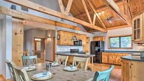 Une cuisine spacieuse dotée de meubles en bois, d’un îlot central et d’un coin repas avec une table et des chaises en bois.