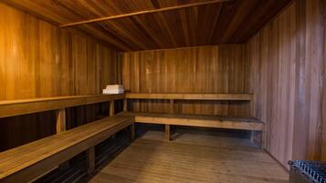 A wooden sauna with benches and a stack of towels.