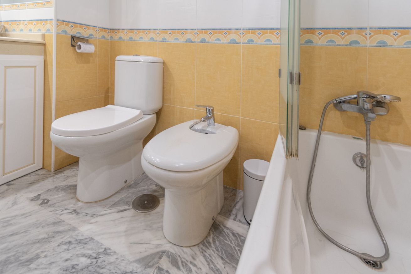 Une salle de bain avec deux toilettes, un lavabo et une douche.