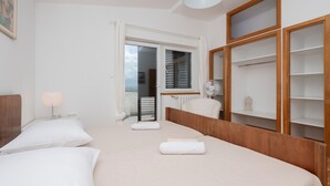 Een hotelkamer met twee bedden, een radiator, een ventilator en een grote houten garderobe.