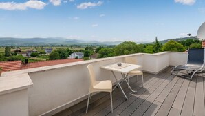 Een balkon met een tafel en stoelen, met uitzicht op een pittoresk landschap met huizen en bergen.