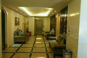 A hotel lobby with a checkered floor, sofas, a trash bin, and a wall-mounted information board. - Sofie Grand Hotel (Wuchuan)