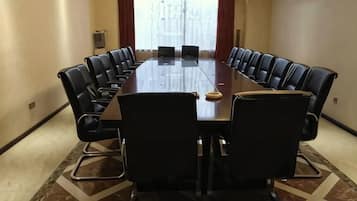 A conference room with a long table, black chairs, and a carpeted floor.