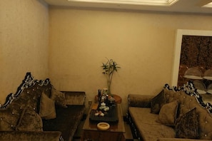 A living room with two sofas, a coffee table, and a decorative plant. - Sofie Grand Hotel (Wuchuan)