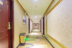 Un couloir d’hôtel avec des portes des deux côtés, une moquette à motifs et un long couloir.