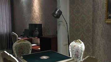 A room with a television, a desk, a chair, and a lamp.